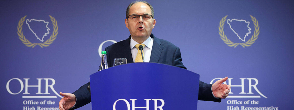 Christian Schmidt standing behind a blue podium with the letters 'OHR' on it.