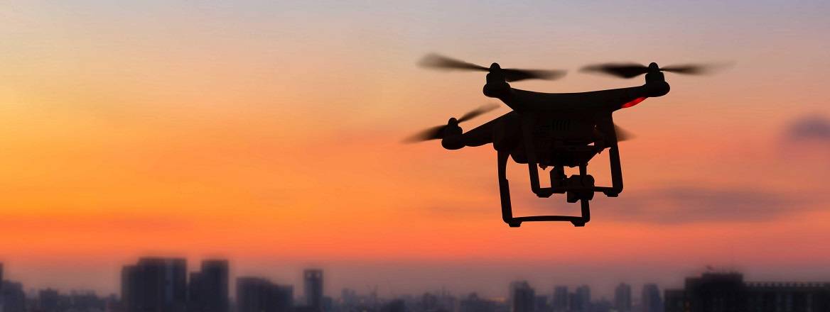 A small UAV flying over a city at dusk