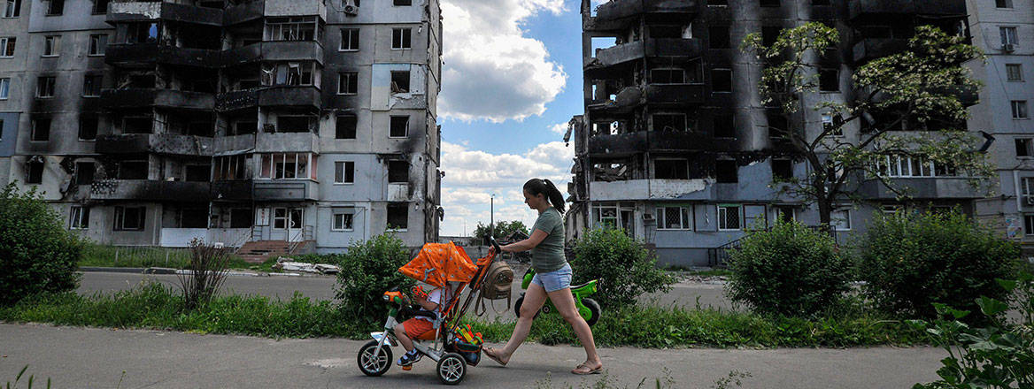 No end in sight: a woman with her child walks past a residential area damaged by Russian shelling in Borodyanka, Ukraine