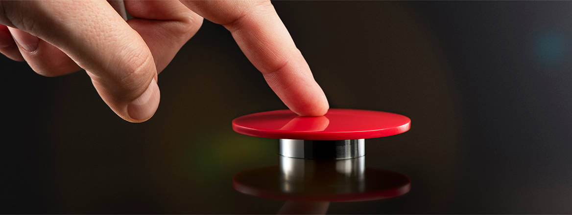 A man's finger presses a big red button as if launching a weapon of mass destruction