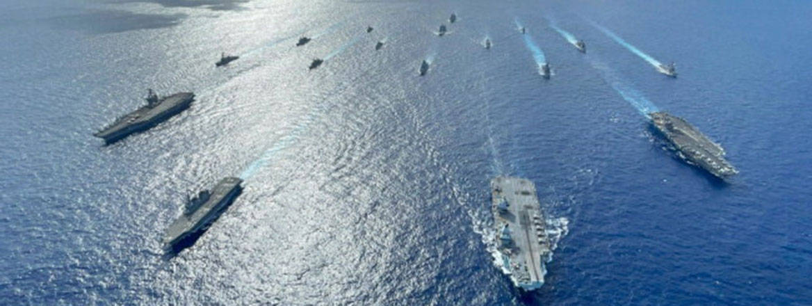 Aerial view of many large naval ships in open water