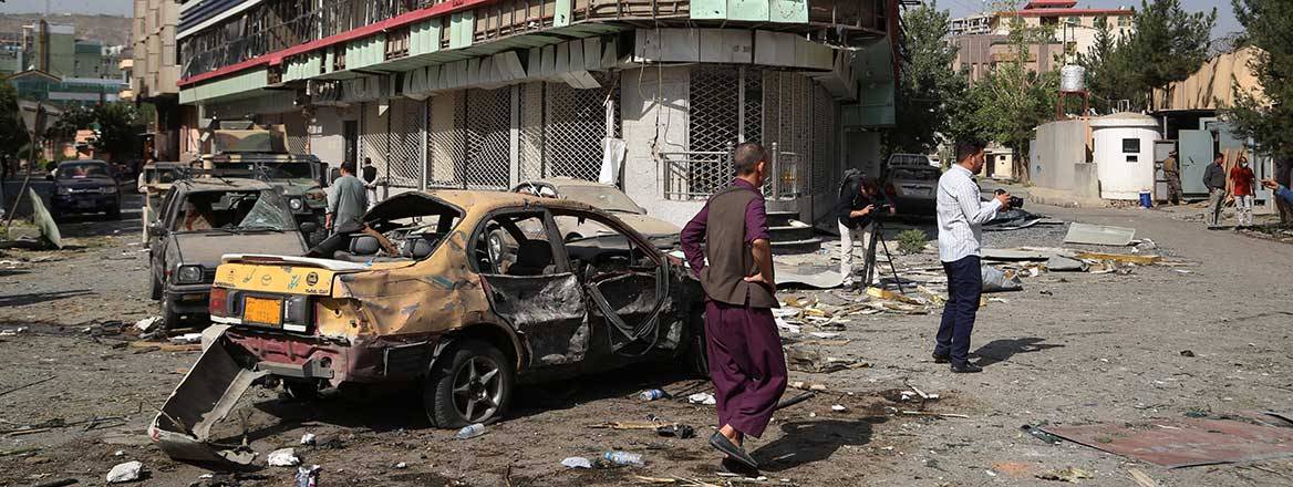 Onlookers surrounding a destroyed vehicle on a street