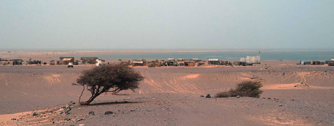 Desert landscape in front of a small village by the sea