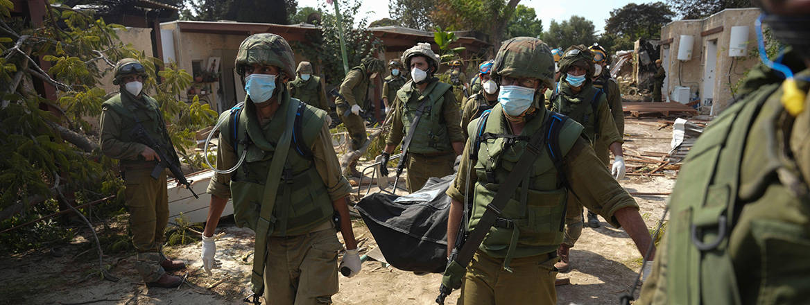 Gruesome toll: Israeli soldiers carry the body of a person killed during the Hamas attack on the Kfar Aza kibbutz on 7 October