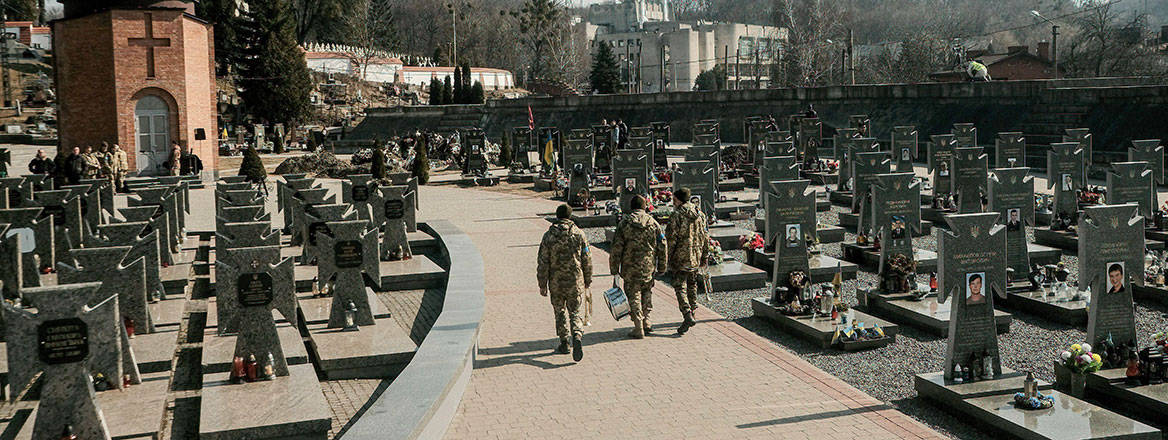 Ukrainian soldiers seen walking through Lychakivske cemetery as they wait for the arrival of the caskets of the four Ukrainian soldiers killed in an airstrike on a military base in Yavariv near the Polish border. Courtesy of Alamy / Zuma Press