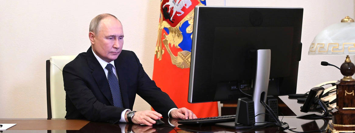 Vladimir Putin sits at a desk in front of a computer to cast his vote in March 2024 election