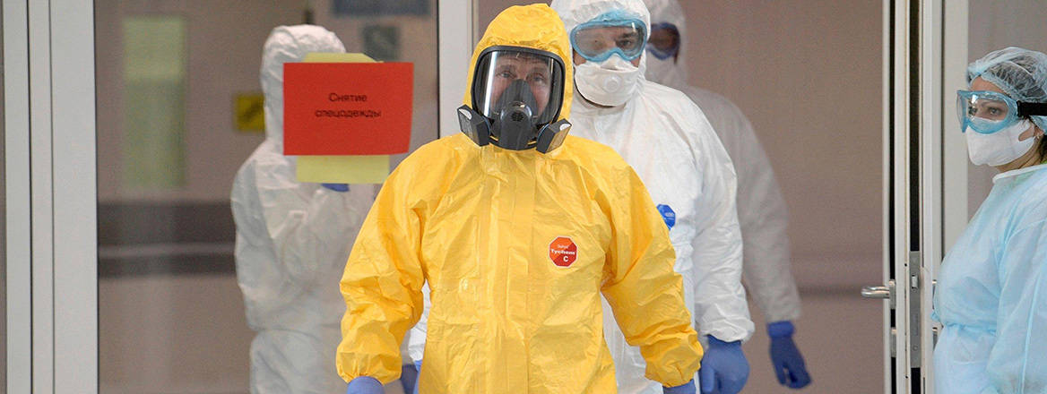 Vladimir Putin walking outside a hospital in a full yellow protective suit. Courtesy of Russian Government / Alamy Stock Photo
