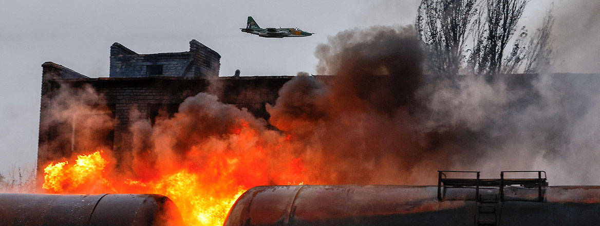 A Russian jet flying above buildings in flames