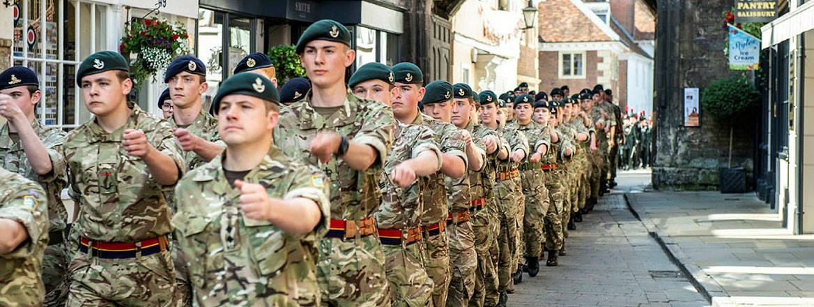 Many soldiers in uniform marching down a street