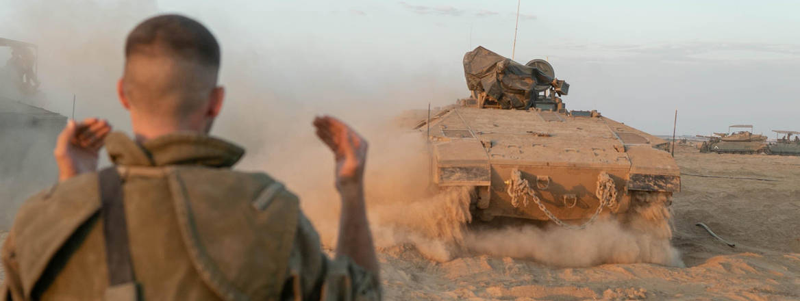 soldier directs tank forward in desert, Gaza, 2023