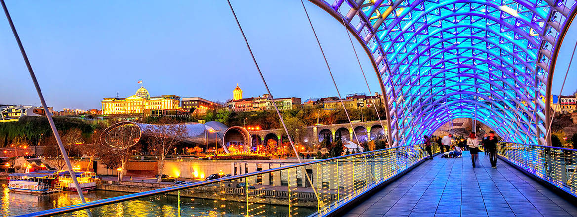 The presidential palace and the peace bridge lit up at night in Tbilisi, Georgia