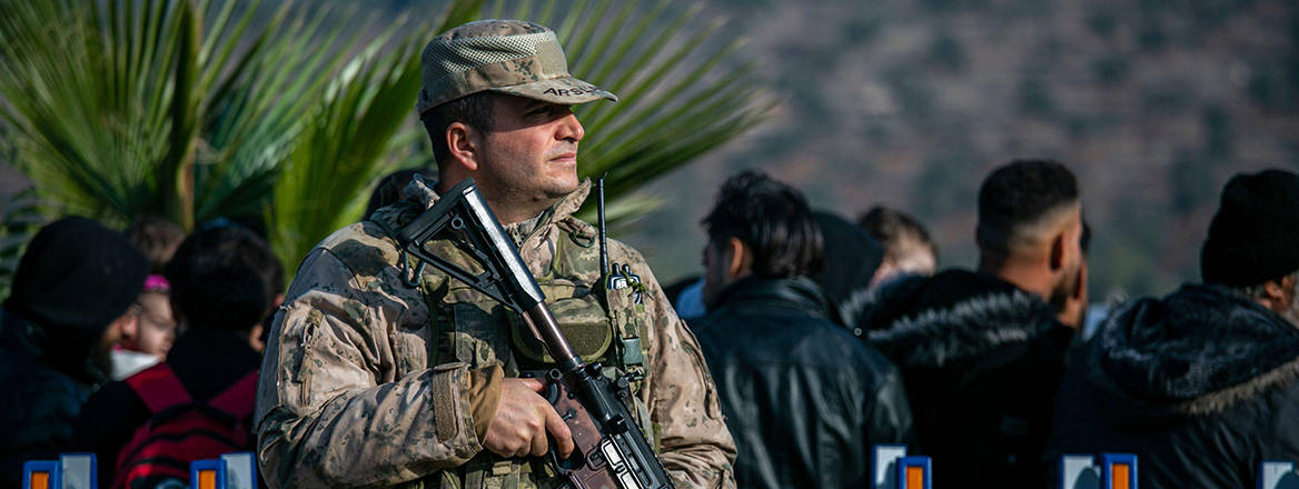 Watchful eye: a Turkish soldier stands guard as Syrians wait to cross the border near the town of Antakya, southern Turkey on 10 December 2024