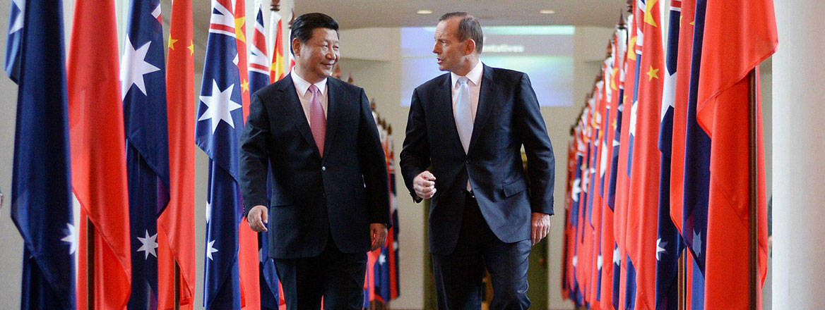 Xi Xinping and Tony Abbott walking in a corridor flanked by Chinese and Australian flags