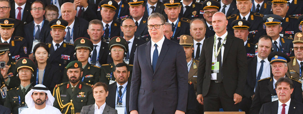 Aleksandar Vucic, President of Serbia, standing at a military parade alongside guests and dignitaries.