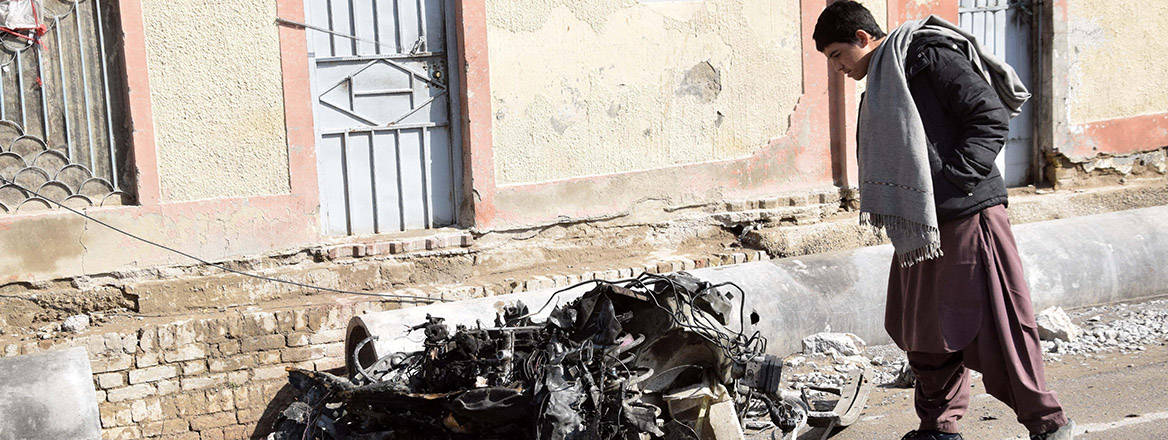 A man looks at the wreckage of a destroyed vehicle at the site of an attack in Quetta.