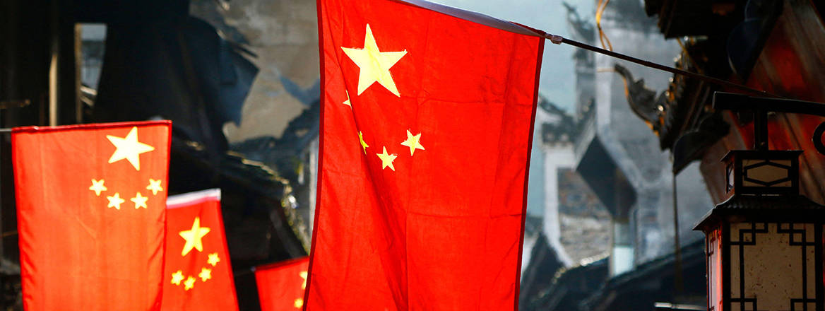 Chinese flags hanging from the eaves of buildings in with an archaic Chinese architecture..