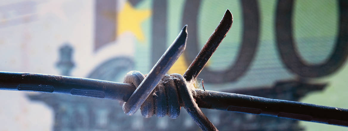 Stock image of barbed wire strung in front of a €100 banknote.