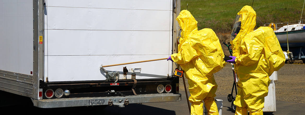 Personnel in hazmat suits inspecting a lorry.