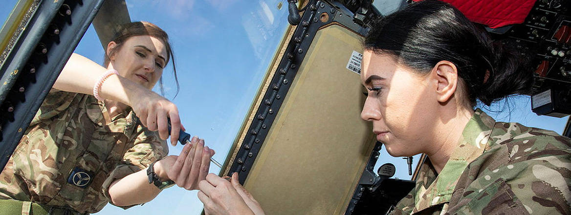 RAF engineers working together to carry out essential maintenance on the cockpit of  a C-130J Hercules transport aircraft.