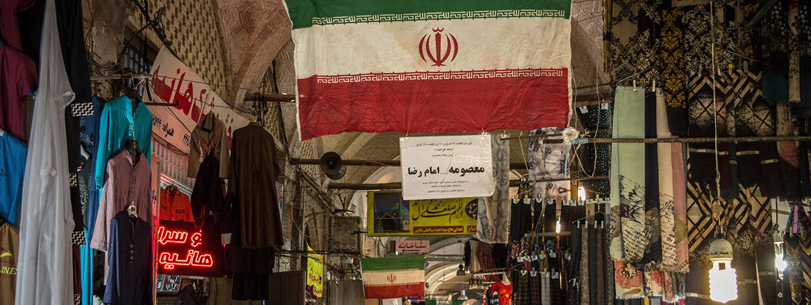 Street of the Isfahan bazar with an Iranian flag hanging, in a covered alley of the market.