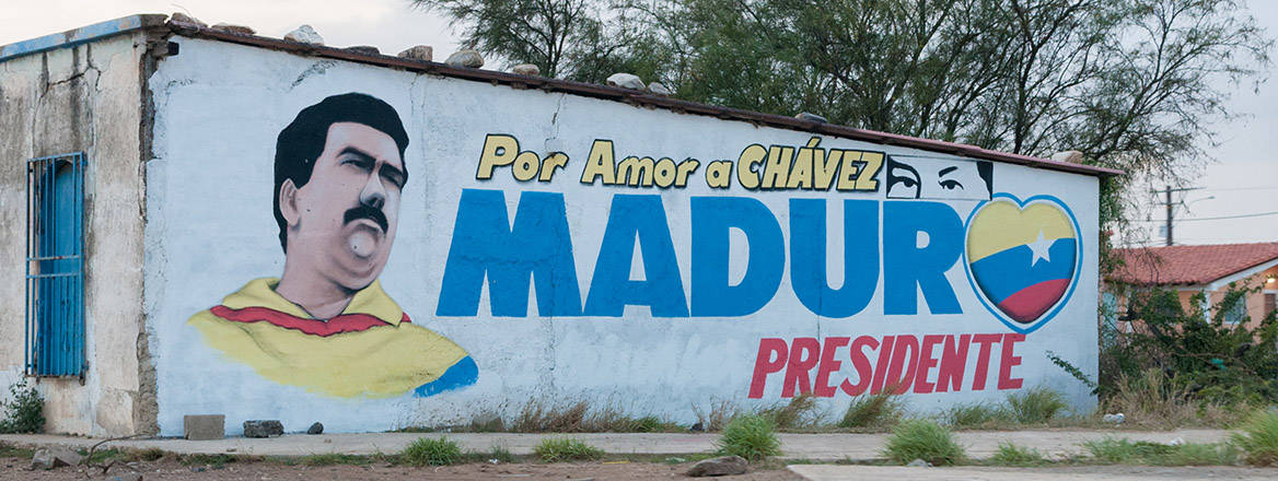A mural on a flat-roofed whitewashed wall shows a portrait of Nicolás Maduro, with the message in Spanish: 'For the love of Chávez, Maduro President'.