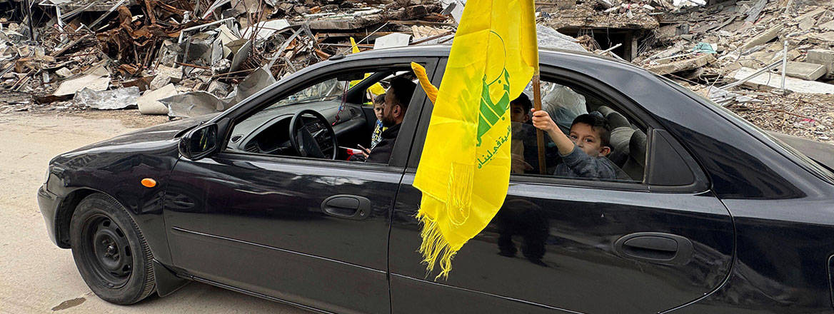 A boy holds a Hezbollah flag, as displaced residents return to Nabatiyeh, southern Lebanon, 28 November 2024, following a ceasefire between Israel and Hezbollah. Courtesy of AP/Alamy