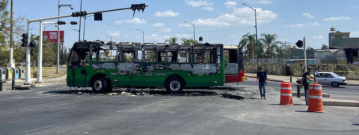 Pedestrians walk past charred buses that were set on fire in Guadalajara, Mexico, 22 February, 2026, after the death of the leader of the Jalisco New Generation Cartel, Nemesio Oseguera Cervantes, known as 'El Mencho'.