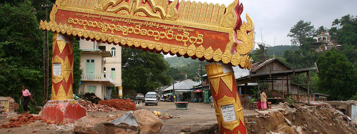 A broken gate in Myanmar on a road that has been heavily damaged.
