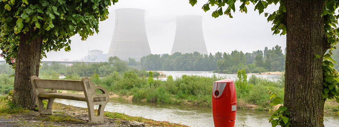 Belleville nuclear power plant on the banks of the Loire in foggy weather with a concrete bench and a fire hydrant on the quay in the foreground.