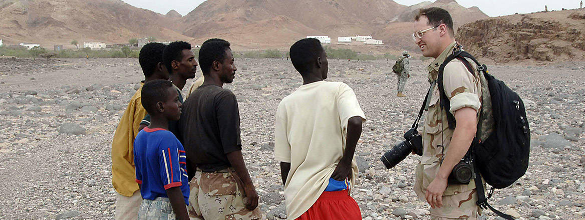 A military photographer with Combined Joint Task Force-Horn of Africa talks with civilians outside the Alaili Dadda base in Djibouti.