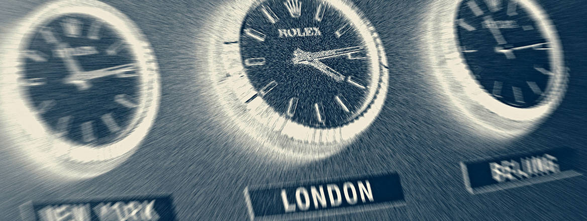 Three office wall clocks with blur effect showing the time zones of New York, London and Beijing.