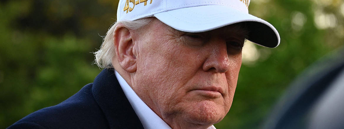 President Donald Trump wearing a white 'Make America Great Again' hat.
