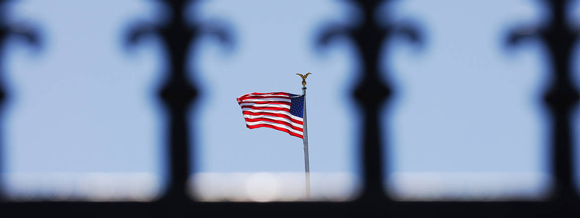 The US flag seen from behind a fence.