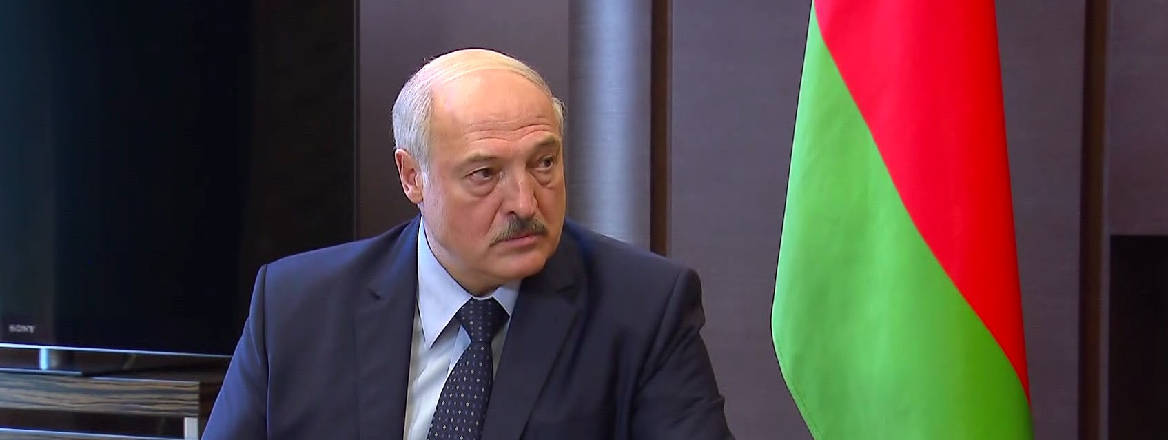 Aleksandr Lukashenko sat next to a Belarusian flag