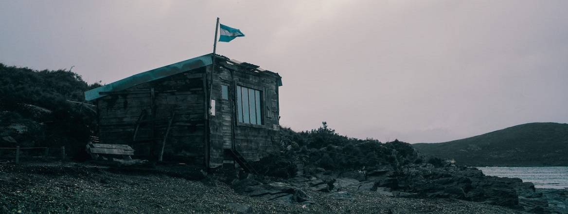 Wooden House with a Flag of Argentina near the Sea