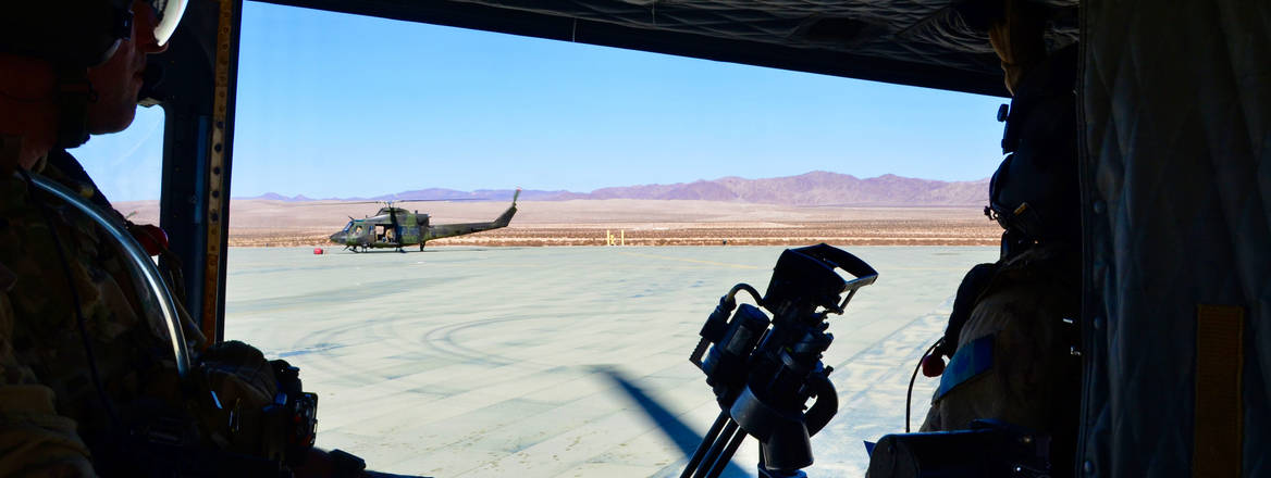 The viewpoint of military helicopter Canadian Griffin crews looking through open door to another helicopter on landing base