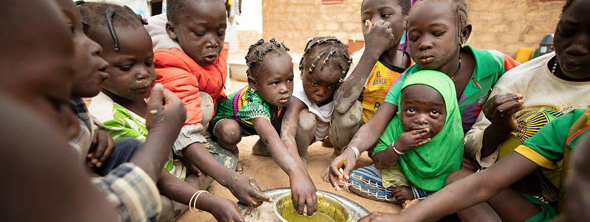 Slim pickings: a group of children displaced by violence in Burkina Faso eat around a communal dish
