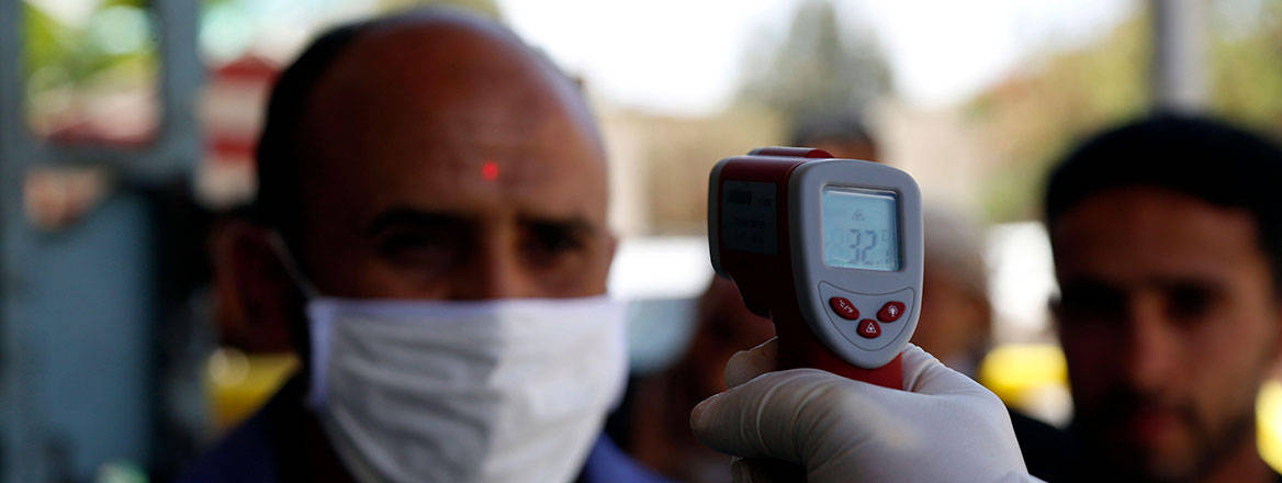 Man wearing mask being checked with a non-contact thermometer.