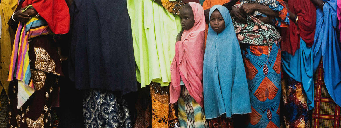 Nigerian girls and women standing together wearing colourful clothing