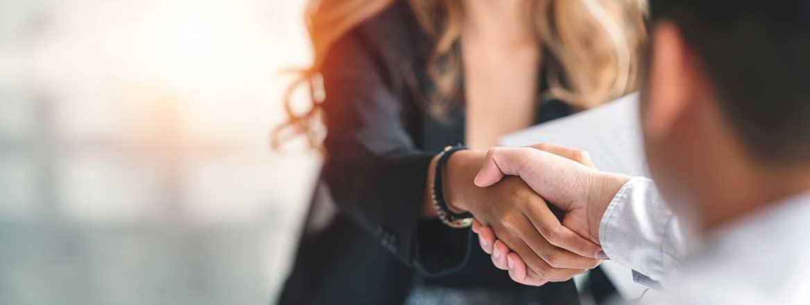 Man and woman shaking hands representing partnerships with academia to counter economic crime