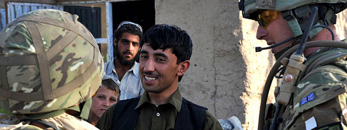 A UK soldier talks to a local shop owner via an interpreter