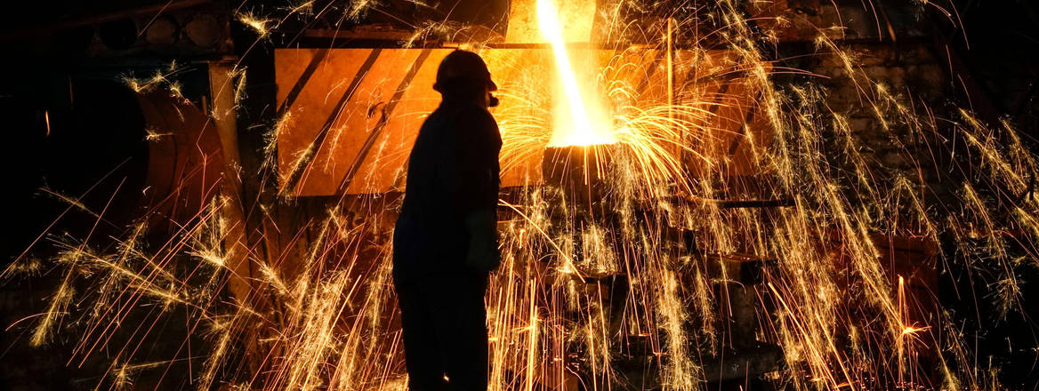 A man pours molten steel into a mold at a foundry 