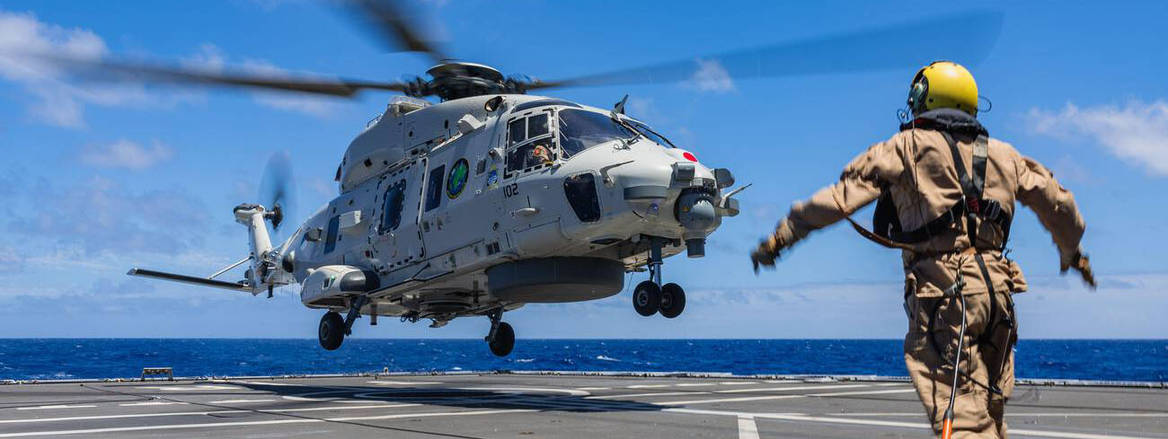 A Royal Netherlands NH90NFH helicopter lands onboard Royal Netherlands Navy De Zeven Provincien-class frigate HNLMS Tromp, with navy staff in foreground
