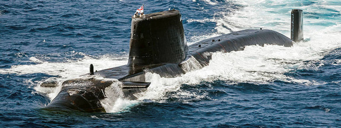 HMS Astute crashes through the waves as it surfaces for photographs with the UK Carrier Strike Group 2025.