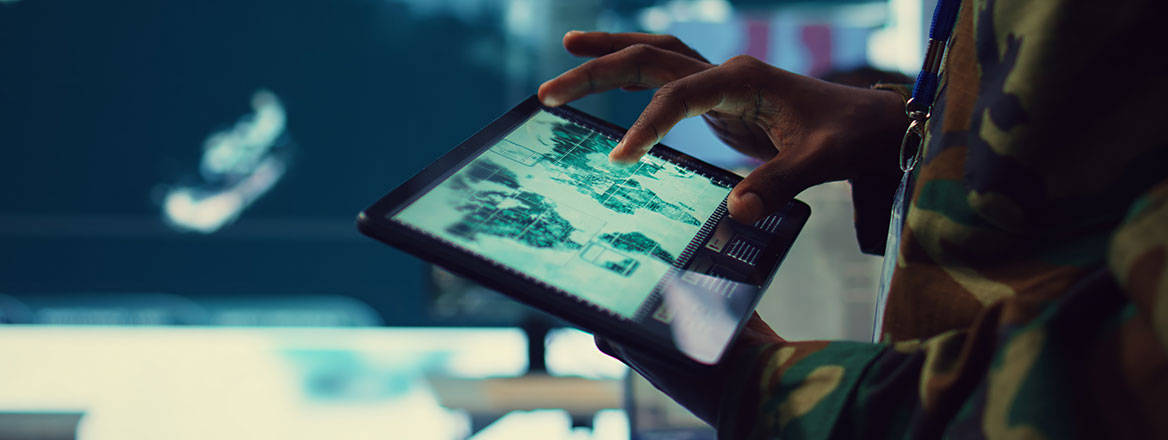 Army soldier reviews targets on a satellite world map. DC Studio / Adobe Stock.