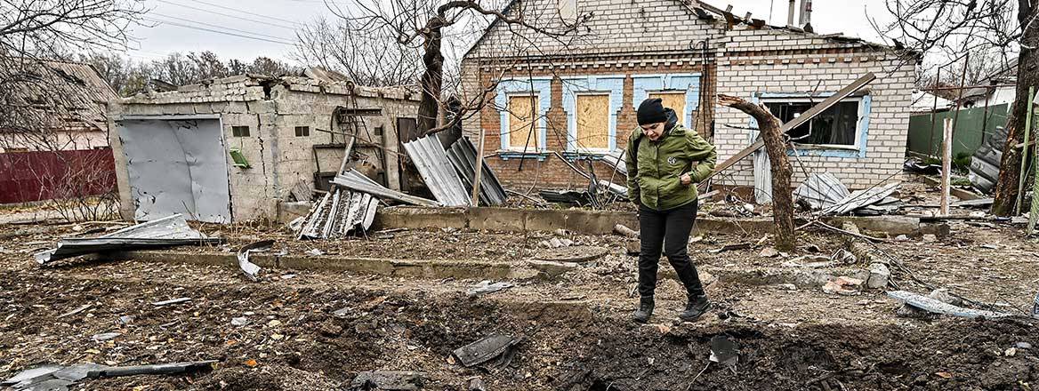 A woman stands by the edge of the crater from the impact of a Russian Shahed drone outside a house in Zaporizhzhia, southeastern Ukraine, 25 November 2024. Courtesy of Ukrinform / Alamy Stock Photo