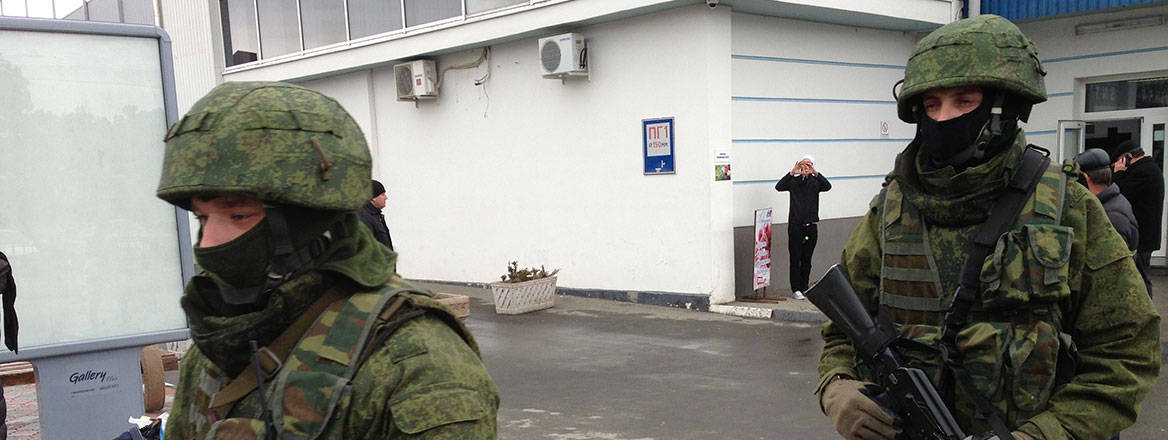 Two unmarked soldiers wearing green uniforms and carrying weapons