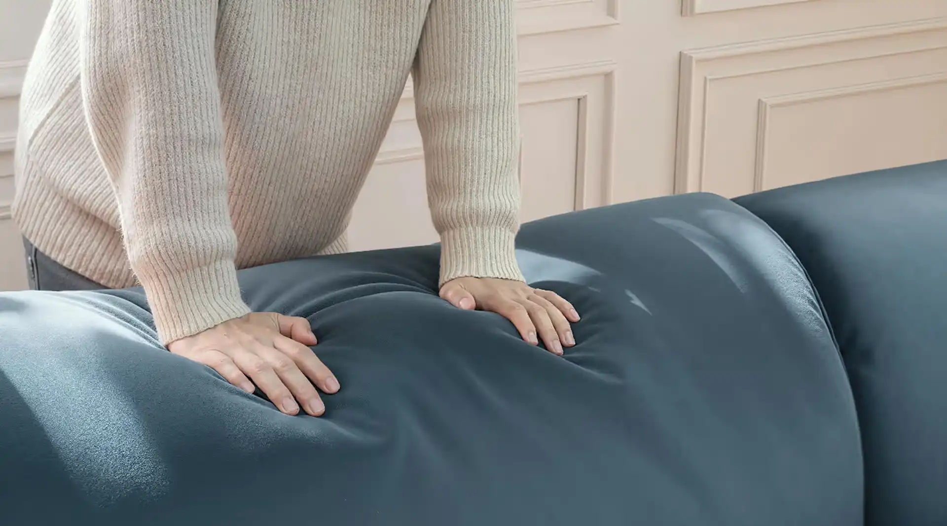 A person pressing down on the durable, soft navy blue sofa cushion, highlighting the upholstery built for daily family use.
