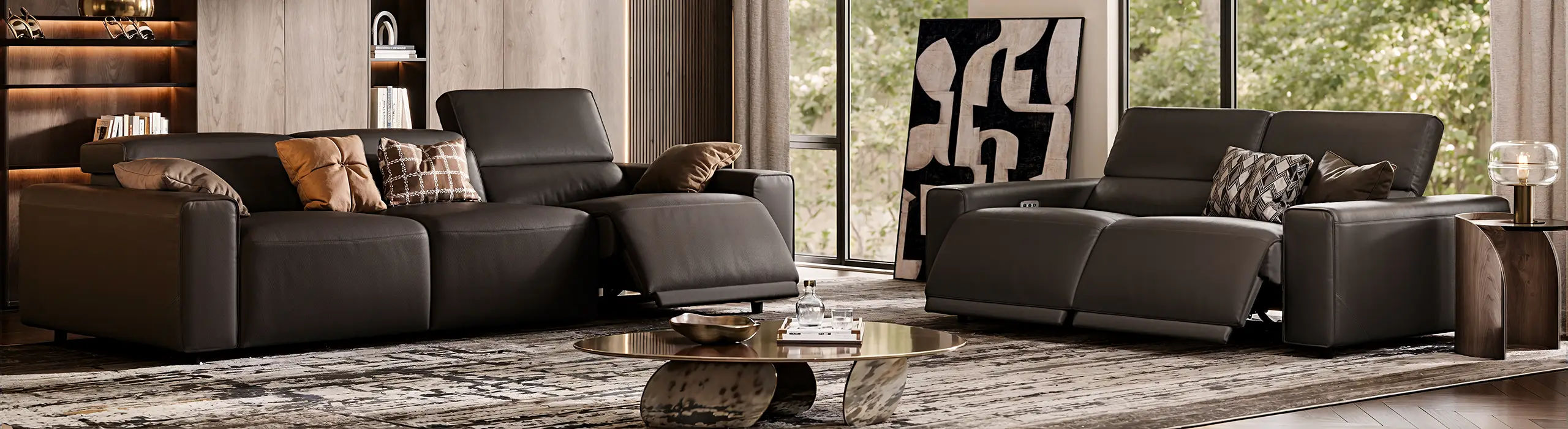 Two dark brown power reclining sofas with extended footrests in a modern living room with large windows and a low coffee table.