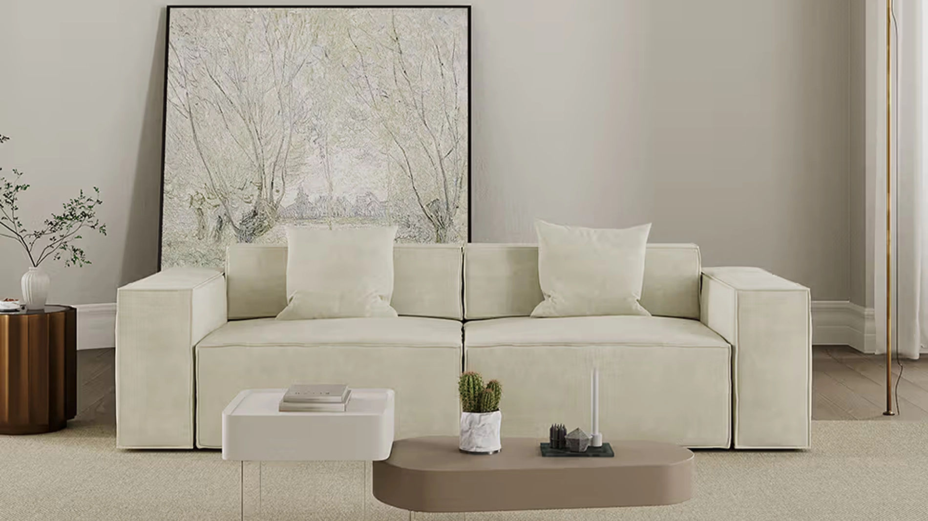 Cream low-back sofa with wide square arms and throw pillows in a minimalist living room with abstract wall art and neutral decor.